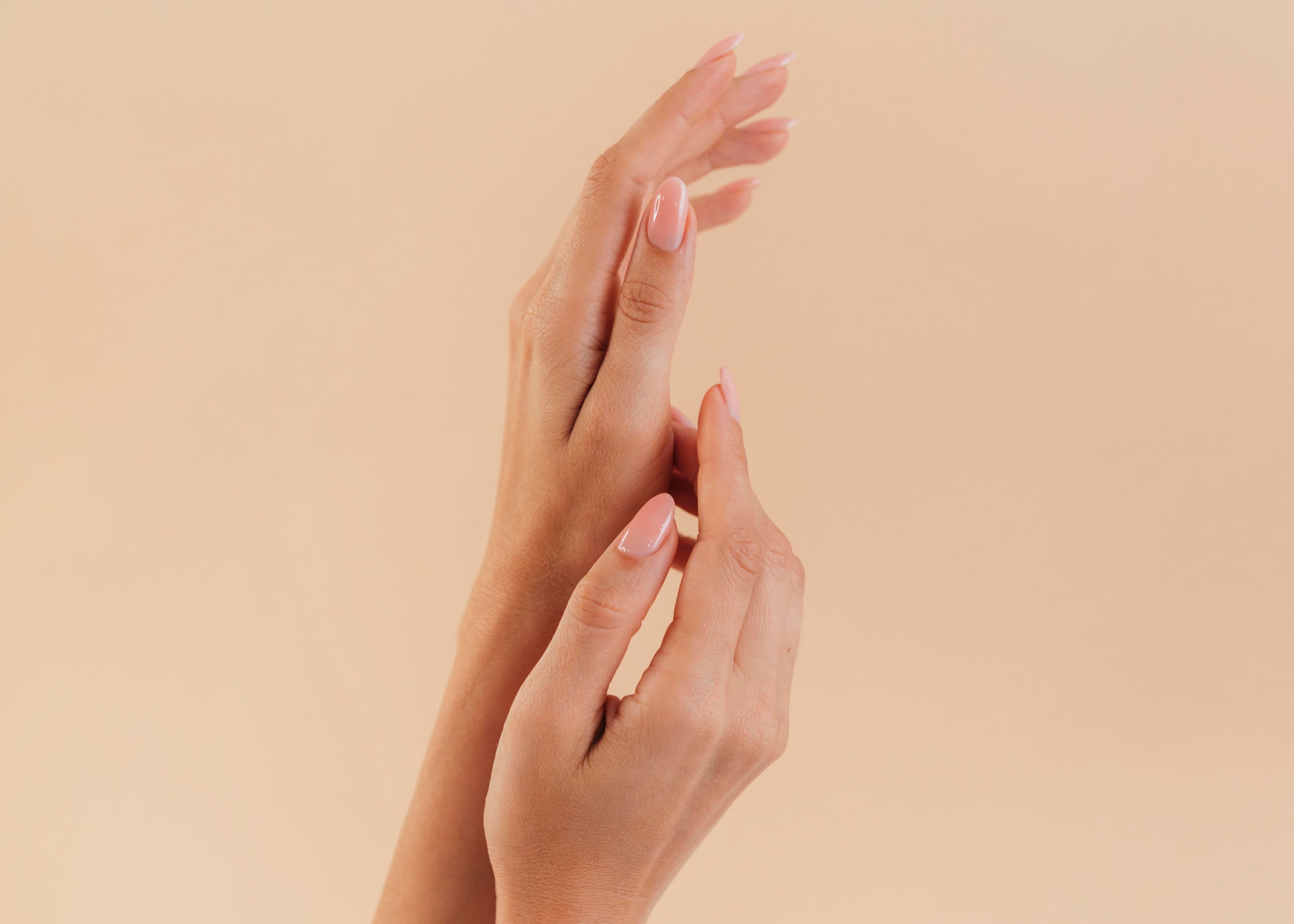 Soft peach manicure highlighted against a neutral backdrop