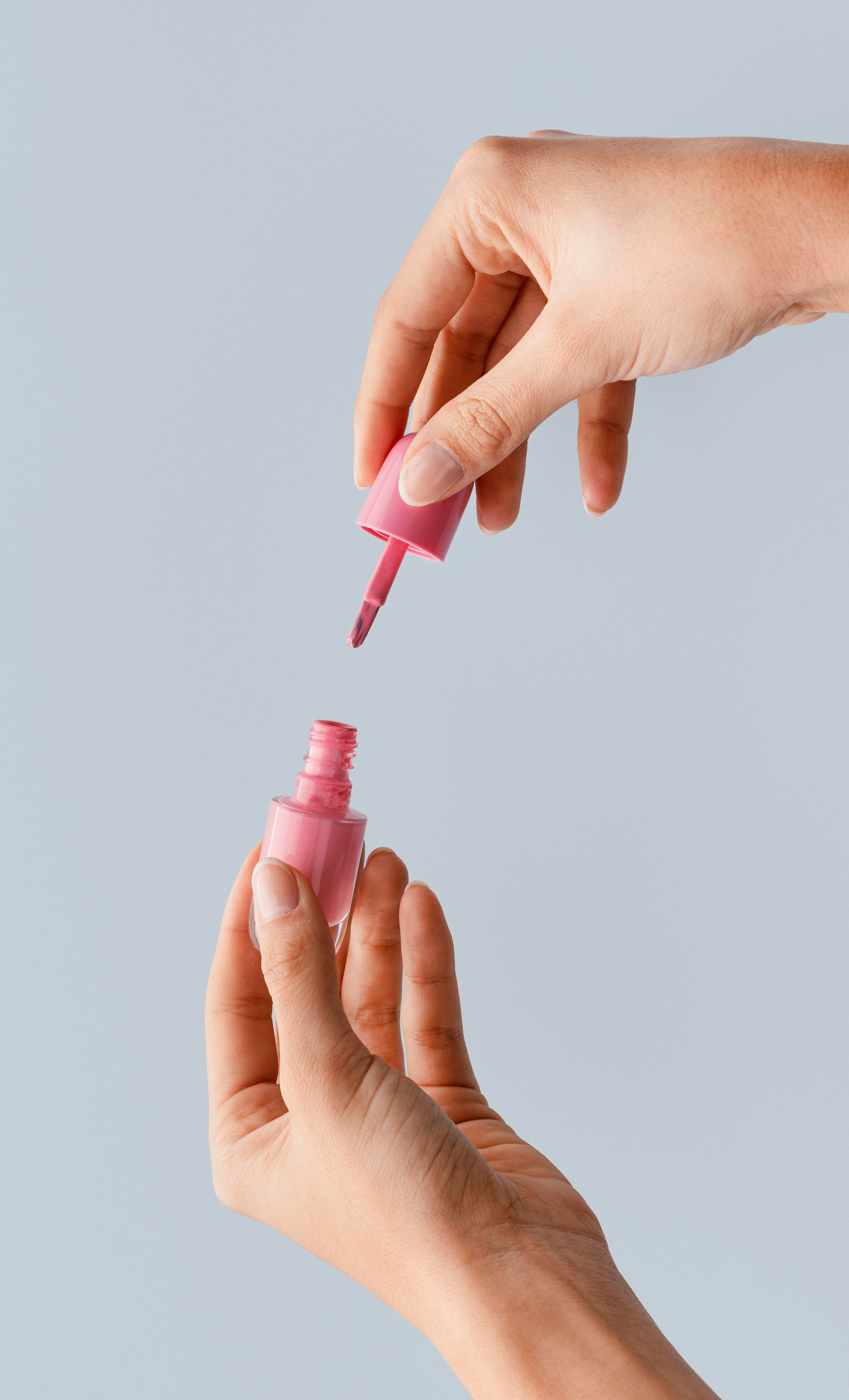 Technician opening a pink gel polish bottle